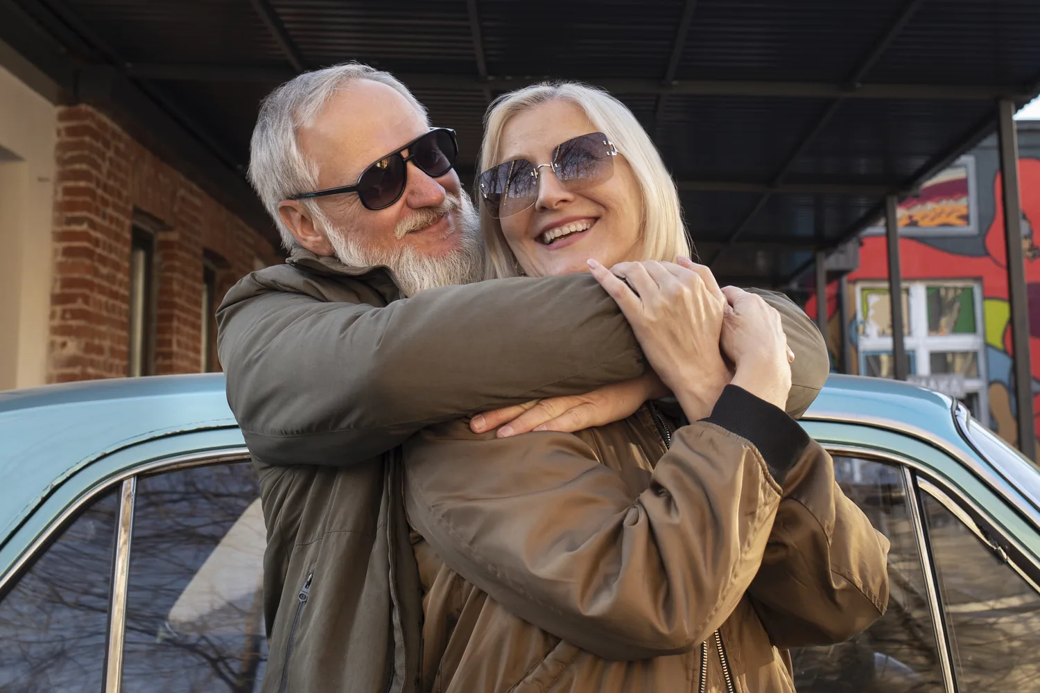 A Different Daily Rhythm: a mature adult couple embracing beside a car